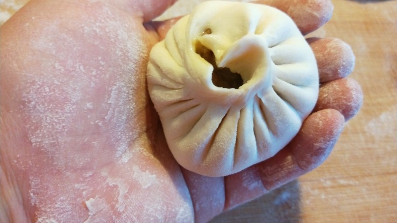 白香菇猪肉包子  新文美食,装入馅料，拇指捏紧，往前推折捏紧。