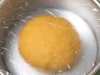 南瓜豆沙味喜饼,厨师机揉面至面粉结团，无需出膜状态。揉面完成整理、滚圆放入模具，盖上保鲜膜。