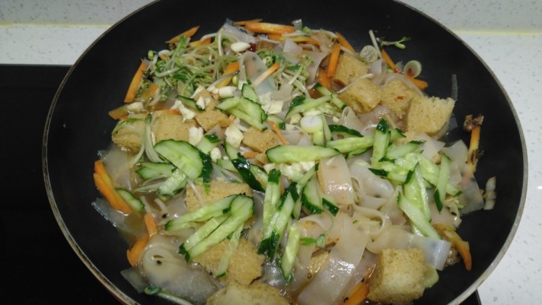 绿豆芽炒凉皮,翻炒均匀，放入黄瓜丝和蒜末。