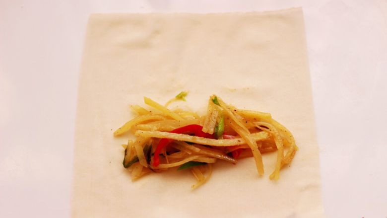 土豆丝红椒煎春卷,取一张春卷皮，放入炒好土豆丝。
