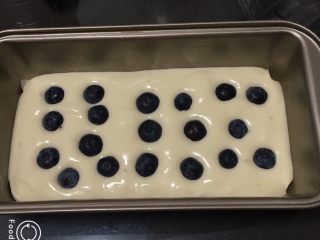 蓝莓玉枕蛋糕,吐司盒中放一张烤盘纸，方便脱模，蛋糕糊倒入模具一半，放入蓝莓。