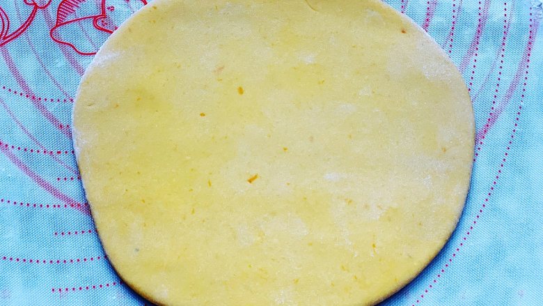 香煎南瓜小馒头,取出发酵好的面团，放在硅胶垫上揉搓排气，撒上少许面粉，然后用擀面棍擀成厚薄均匀的圆形，厚度大概在1cm左右。