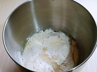 果仁面包卷,最后加入高筋面粉，在面粉的顶端挖个洞，把酵母粉加入洞洞里，再用周边的面粉盖起来。