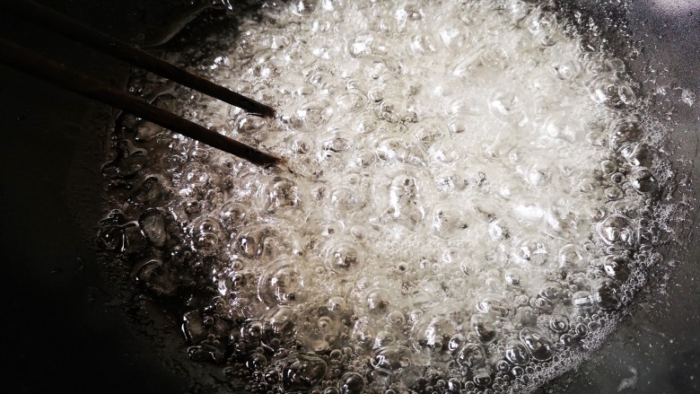 柚子皮糖,中火煮开后转小火，一边煮一边用筷子慢慢轻搅动加速冰糖融化，直至糖浆起密集的大泡。