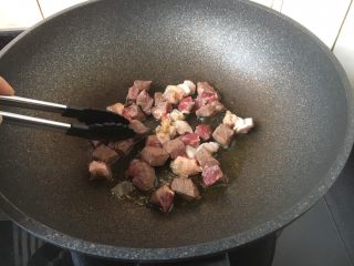 黑胡椒牛肉粒,将牛肉粒一面煎至变色，用夹子将牛肉粒反过来，煎另外一面，同样煎至变色。