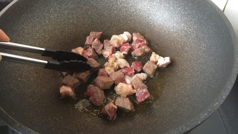 黑胡椒牛肉粒,将牛肉粒一面煎至变色，用夹子将牛肉粒反过来，煎另外一面，同样煎至变色。