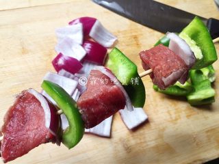 烤牛肉串,随后把腌好的牛肉、洋葱、青椒，串到竹签上。
