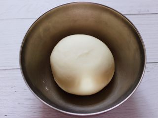 大葱猪肉发面包,和好的面团从面包机取出来后用手揉圆，放到盆里，盖上保鲜膜进行醒发。