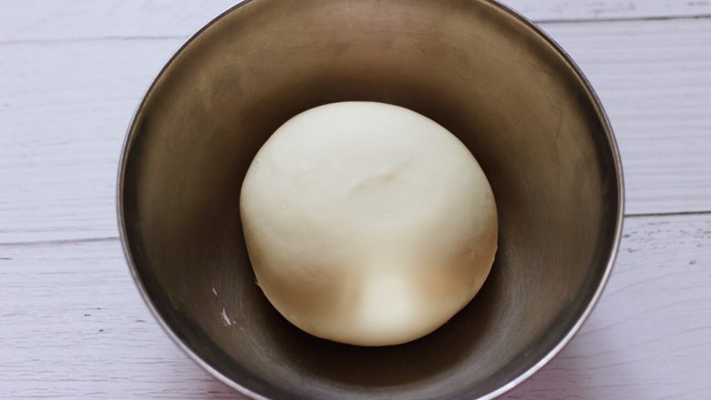 大葱猪肉发面包,和好的面团从面包机取出来后用手揉圆，放到盆里，盖上保鲜膜进行醒发。
