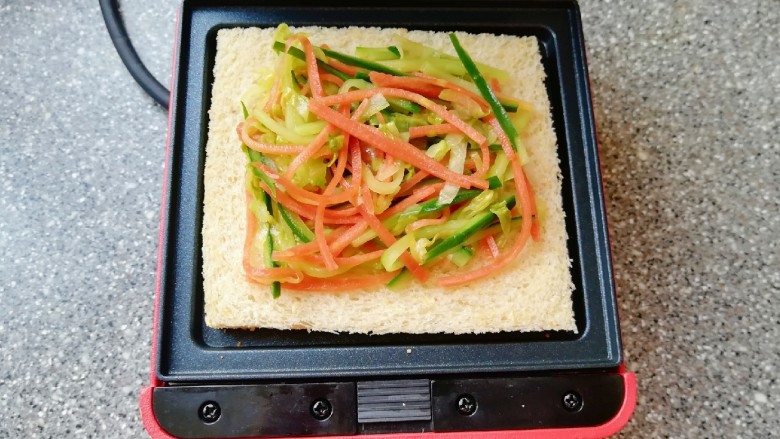 全麦蔬菜三明治,预热好的三明治早餐机下盘放上一片全麦吐司，放上炒好的蔬菜。