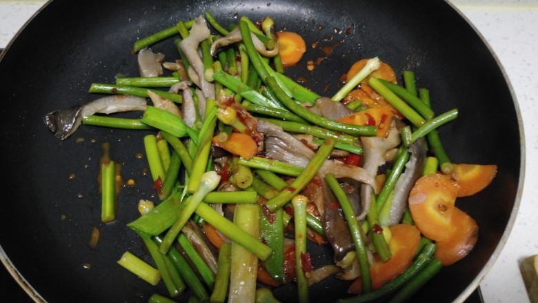 蒜苗炒蒜苔、胡萝卜、平菇,加入蒜苗叶翻炒均匀。