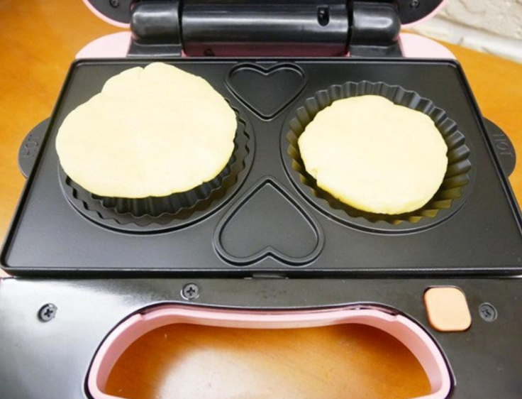 卡士达草莓塔,松饼机热机后将面团压扁放入烤盘内，烤约3分钟即可取出。