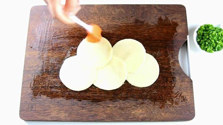 包饺子剩下的饺子皮别浪费，还能做葱油饼哦,取5张饺子皮交错叠起，抹上猪油。