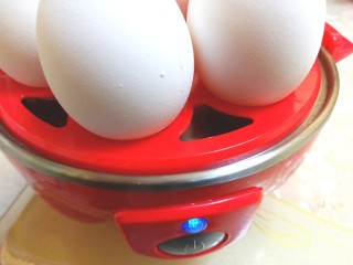 牛油果鸡蛋沙拉杯,煮蛋器插电，按下开关，指示灯亮了，盖好盖子开始煮蛋