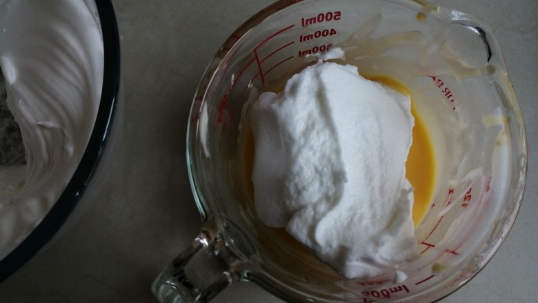 香草舒芙蕾,蛋清用电动打蛋器打至粗泡时，分两次加入剩余的细砂糖，打发至干性发泡的蛋白霜。取1/3打发好的蛋白霜打蛋黄糊里，从底部向上翻拌并切拌均匀