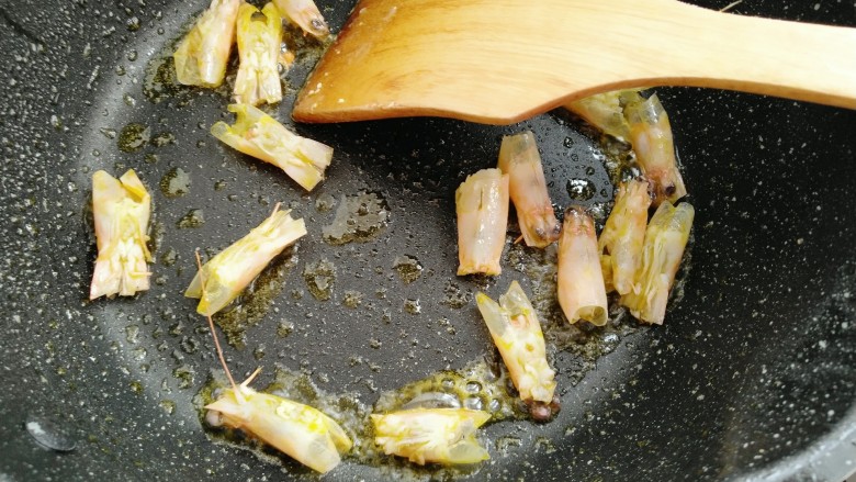 鲜虾滑蛋炒碗豆,锅中放油放入虾头炒香