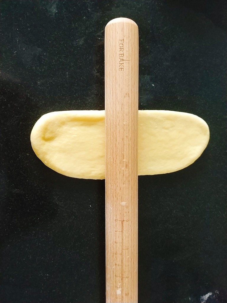 南瓜泥奶香吐司,再把面剂子用擀面杖擀成椭圆形，长度得够卷起两圈半，宽度小于吐司盒子宽；