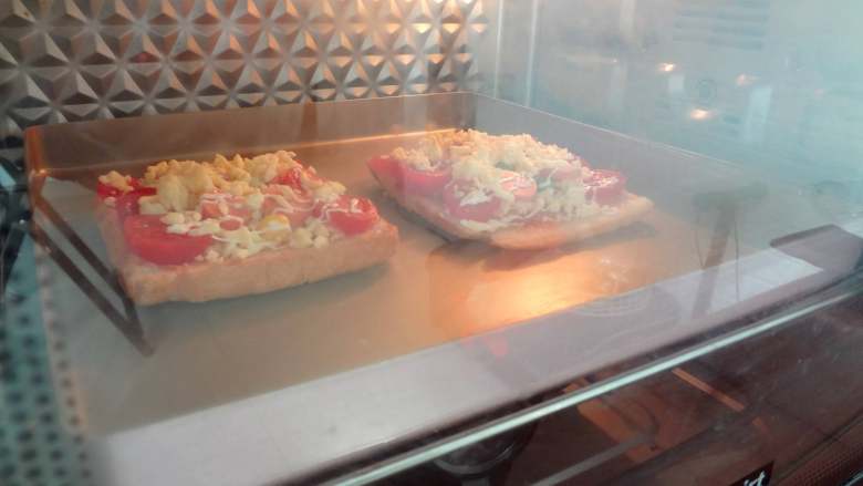 快手早餐-吐司披萨,放在烤盘上送入预热好的烤箱180度15分钟，芝士融化即可享用啦！