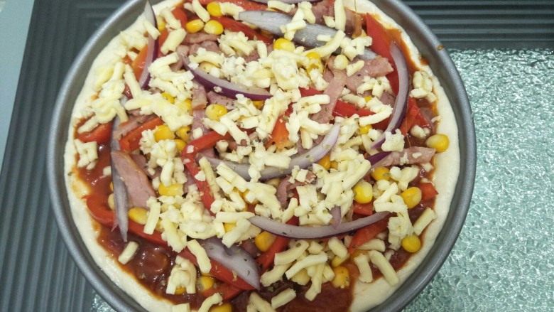 培根蔬菜披萨,放入煮好的蕃茄酱料，再放入马苏里拉，放入培根，洋葱，玉米最后铺上<a style='color:red;display:inline-block;' href='/shicai/ 61855'>马苏里拉芝士</a>，放入预热好的160度烤箱烤25分钟。