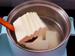 香辣煎豆腐,东菱早餐机的汤锅中，加入适量的清水烧开，加入一勺盐，放入切片的豆腐。