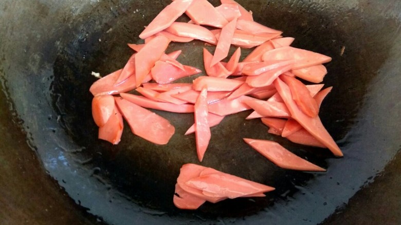土豆青椒炒火腿,锅中放入少量植物油 ，放入火腿片翻炒至焦黄