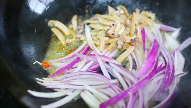 墨鱼杂蔬炒螺丝意面,锅中加入30克玉米油烧热后倒入墨鱼、洋葱一起煸炒出香味。