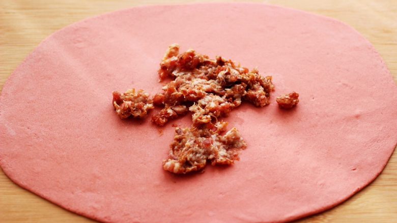 蒜香粉嫩肉龙花卷,把搅拌好的肉馅倒入面皮上。