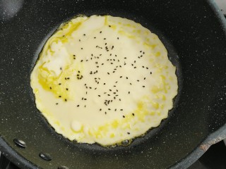 煎蛋饼,热锅小火刷一层薄油倒入面糊摊均撒上芝麻
