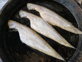 椒盐鳎米鱼,平底锅中适量的油烧热后，将拖好粉的鳎米鱼放入锅内，中小火煎。