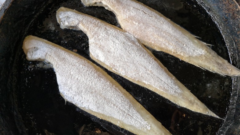 椒盐鳎米鱼,平底锅中适量的油烧热后，将拖好粉的鳎米鱼放入锅内，中小火煎。