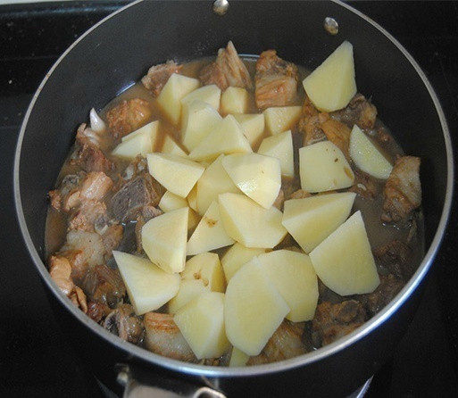 土豆烧排骨,打开盖子放入土豆翻炒均匀，再盖上盖子焖煮10-15分钟即可；