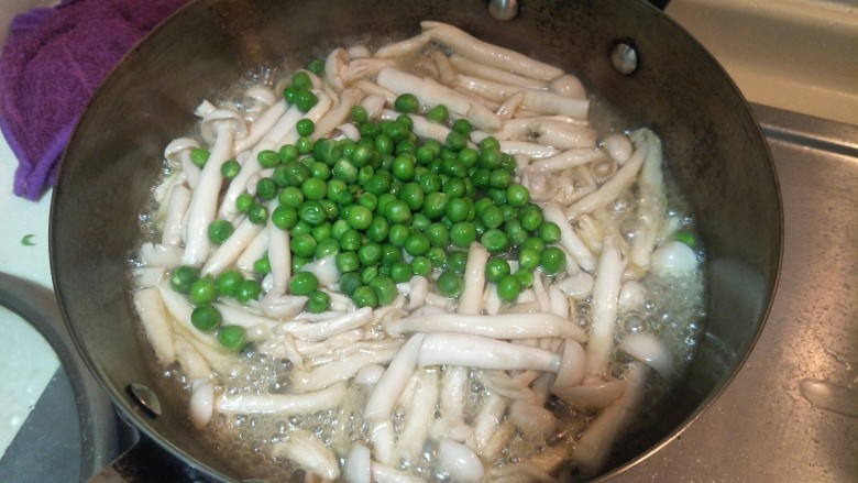 健康低卡香煎鲈鱼,继续把刚刚煮好的小豌豆放入锅中。菇会炒出水分。