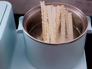 时蔬海虾刀削面,东菱早餐机的汤锅里，加入适量的清水煮沸后，放入刀削面。