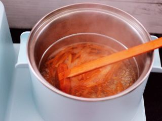 鹅蛋菠菜早餐饼,东菱早餐机的汤锅里，加入适量的清水煮沸后，加入切丝的胡萝卜焯一下水。