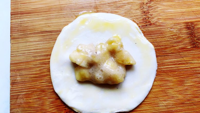 懒人版香蕉酥,在压好的饼皮上面舀上1小勺香蕉馅，饼皮靠外的一圈刷上提前打散的鸡蛋液，这样更好粘合。