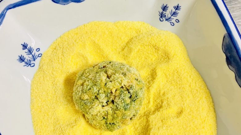 玉米面菜团子,取一个小菜球 让小菜球全部粘上玉米面粉。