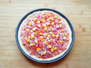 培根肉披萨,均匀的撒上洋葱、红萝卜和玉米粒。