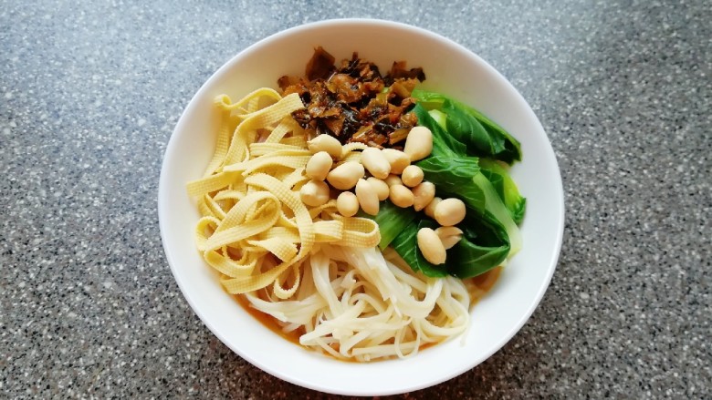 牛骨汤酸菜米线,泡好的米线煮熟放入碗里，放入青菜、金针菇、豆腐皮和炒好的酸菜，最后放上花生米。