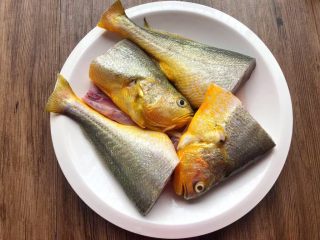 酸菜炖黄鱼,把黄鱼清洗干净，特别是肚子里的黑膜要清洗干净，然后再切成两段。