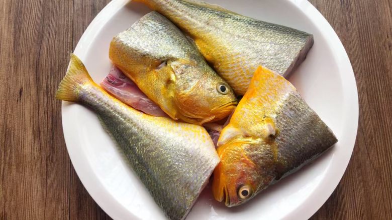 酸菜炖黄鱼,把黄鱼清洗干净，特别是肚子里的黑膜要清洗干净，然后再切成两段。