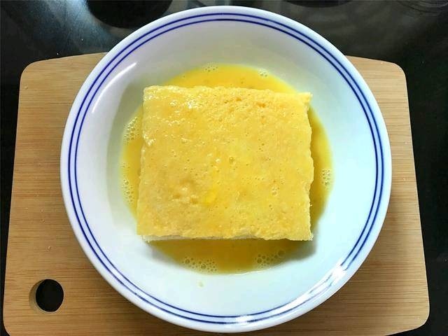 芒果酸奶土司,把夹入水果的吐司放入鸡蛋液中，上下和四周都均匀地裹上一层蛋液.