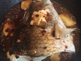 头菜炆鲩鱼,鱼身煎至金黄后，放入姜片，料酒，再把拌匀的酱料倒入锅中