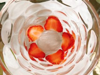 草莓奶昔,取2个差不多大小的草莓对半切开，再切成薄片贴在透明杯子底部。
