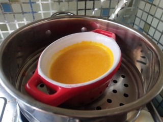 蛋黄南瓜蒸蛋,盖上保鲜膜扎眼，放入锅中蒸10分钟。