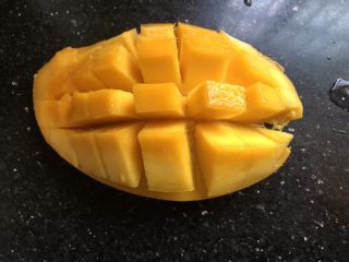 芒果酸奶奶昔,芒果对半切开，取一半用刀划成如图形状。