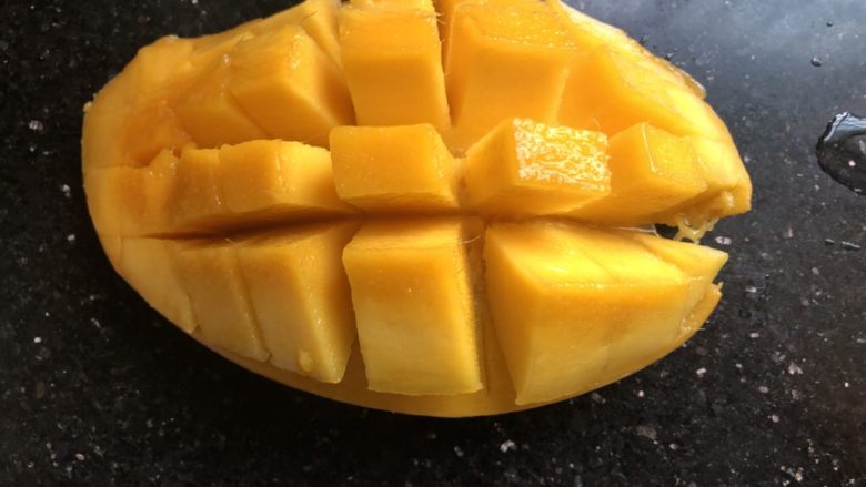芒果酸奶奶昔,芒果对半切开，取一半用刀划成如图形状。