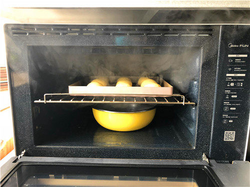 南瓜小餐包,把烤盘放到烤箱，下面放一盆热水，进行二次发酵。
