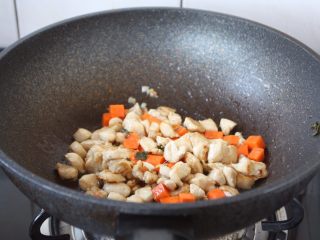 咖喱土豆鸡丁饭,放入胡萝卜丁和鸡丁，翻炒均匀。