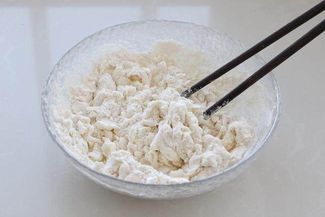 油泼剪刀面,将面粉放入大碗中，调入少许盐，然后一边加入清水一边用筷子搅拌成棉絮状；
