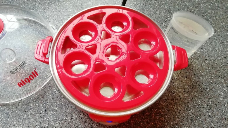 菠菜鸡蛋糕,准备好煮蛋器，放上蛋托盘，用量杯取最高水位的水加入到蒸盘里面。